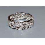 A modern 750 white metal and diamond set pierced foliate ring, size N.