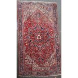 A Heriz red ground rug, with field of geometric and foliate motifs and five row border, 15ft 4in