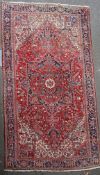 A Heriz red ground rug, with field of geometric and foliate motifs and five row border, 15ft 4in