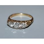 A diamond three-stone ring, claw-set in yellow metal with scrolled mount, size M.