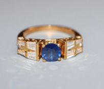 A modern 750 yellow metal, single stone sapphire dress ring, flanked with round and trapeze cut