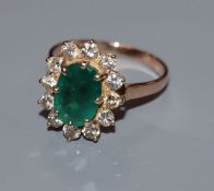 A yellow metal, emerald and diamond set oval cluster ring, size Q.