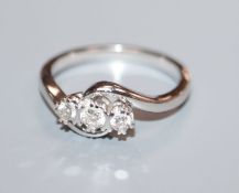 A modern 18k white gold and three stone diamond crossover ring, size O.