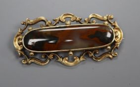 A Victorian yellow metal and agate ovoid brooch, with scrolling border, 72mm.
