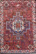 A Shiraz design red ground rug, with central polygon in a field of flower heads and three row