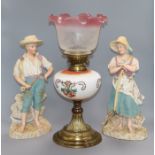 A pair of French coloured biscuit figures and an oil lamp