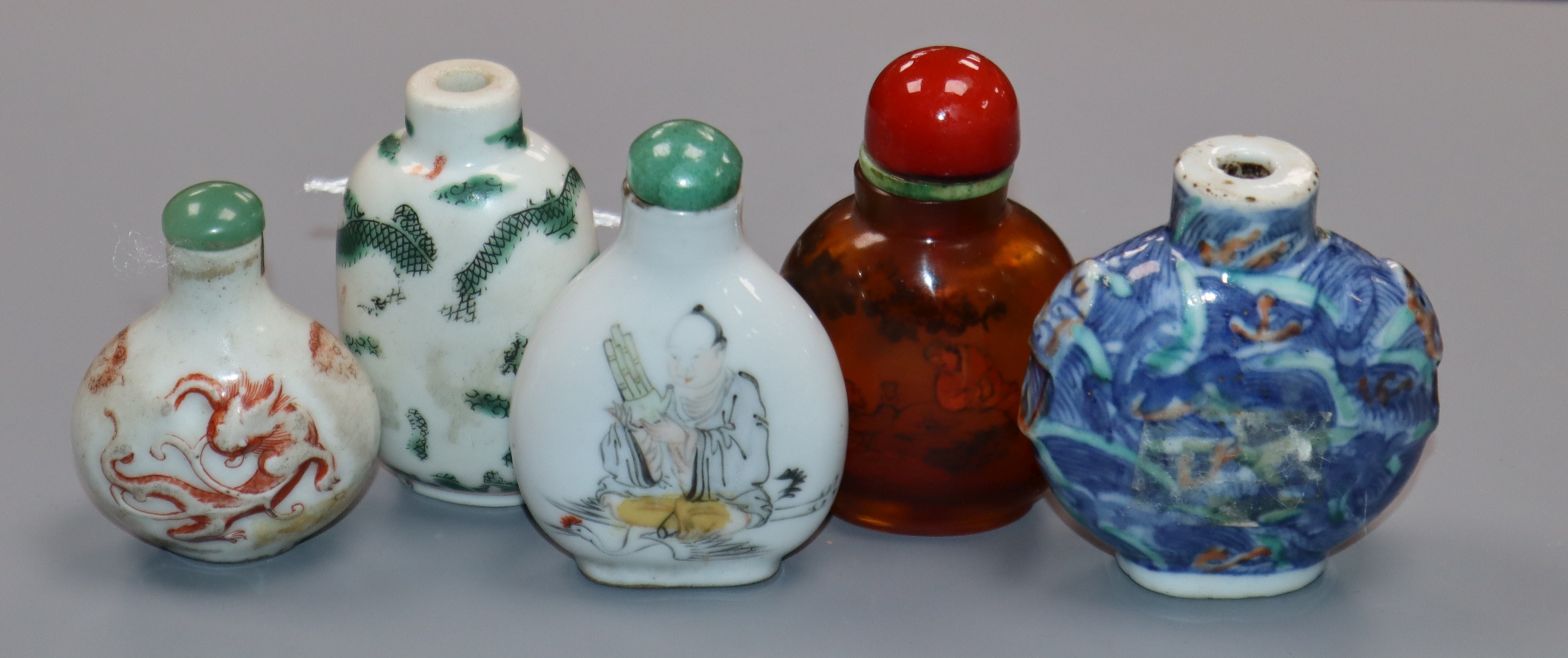 Four 19th century porcelain snuff bottles and an inside painted amber glass snuff bottle