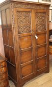 A 1920's carved oak two door wardrobe W.111cm