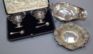 A George V silver sauceboat, a pierced silver bonbon dish and a cased pair of silver salts.