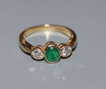 A three stone emerald and diamond ring, 18ct gold setting and shank, size J.