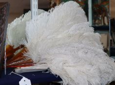 Two white ostrich feather fans, one with gold-monogrammed blond faux-tortoiseshell guard sticks