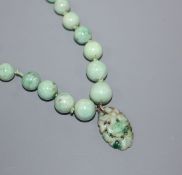 A single strand graduated jadeite bead necklace with carved pendant drop and 9ct clasp, 62cm.