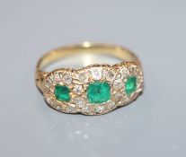 A yellow metal, diamond and emerald triple cluster dress ring, size M/N.