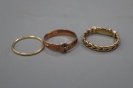 A 14k yellow metal band and two other yellow metal rings including a buckle ring.