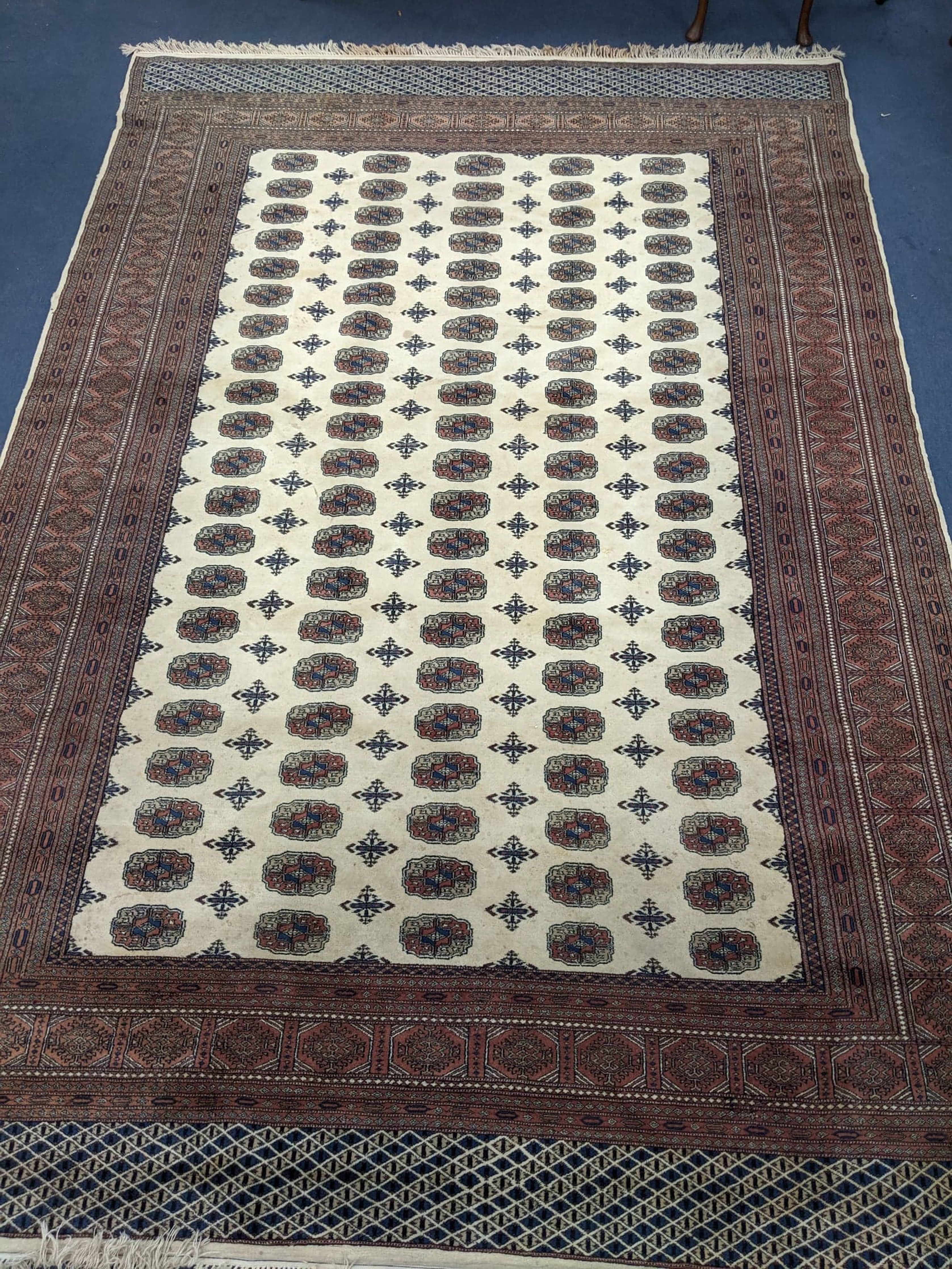 A Bokhara style ivory ground carpet 350 x 240cm