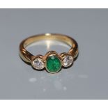 A three stone emerald and diamond ring, 18ct gold setting and shank, size J.