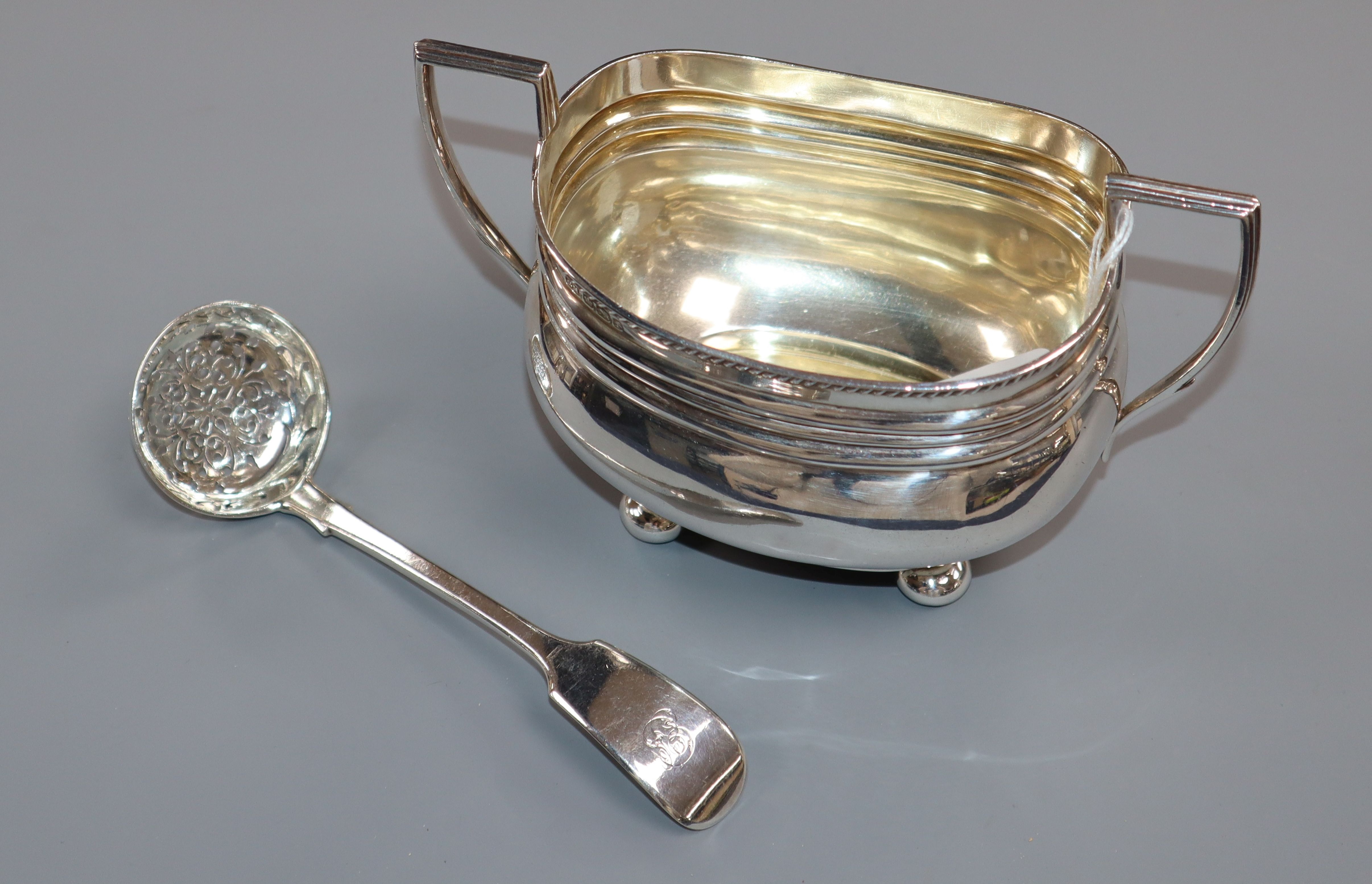 A George V silver sugar bowl and a Victorian silver fiddle pattern sifter spoon.