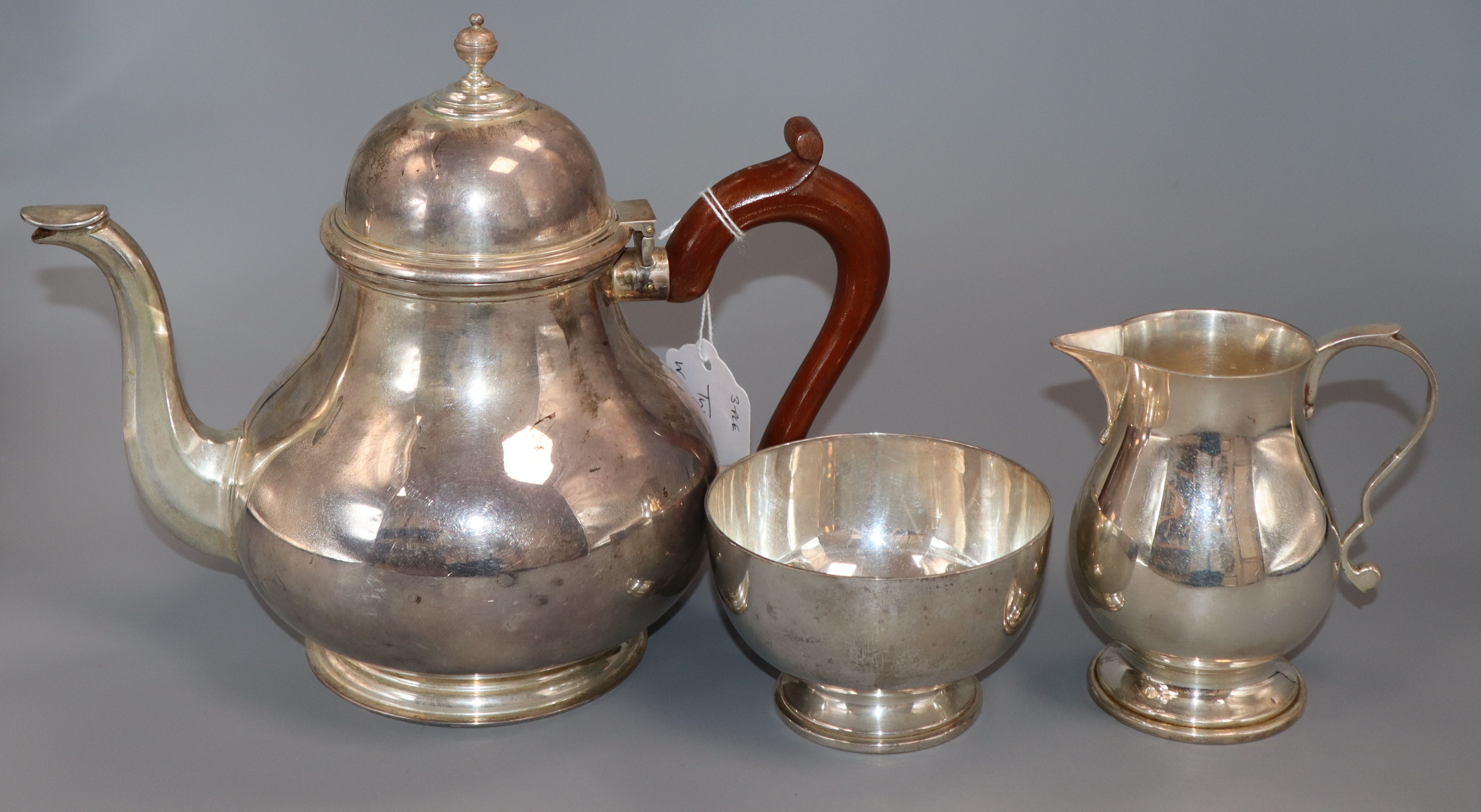 A Queen Anne style silver three-piece tea service, comprising teapot with scrolled wooden handle,