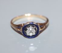 A late Victorian yellow metal solitaire diamond and blue enamel ring, size N.