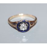 A late Victorian yellow metal solitaire diamond and blue enamel ring, size N.