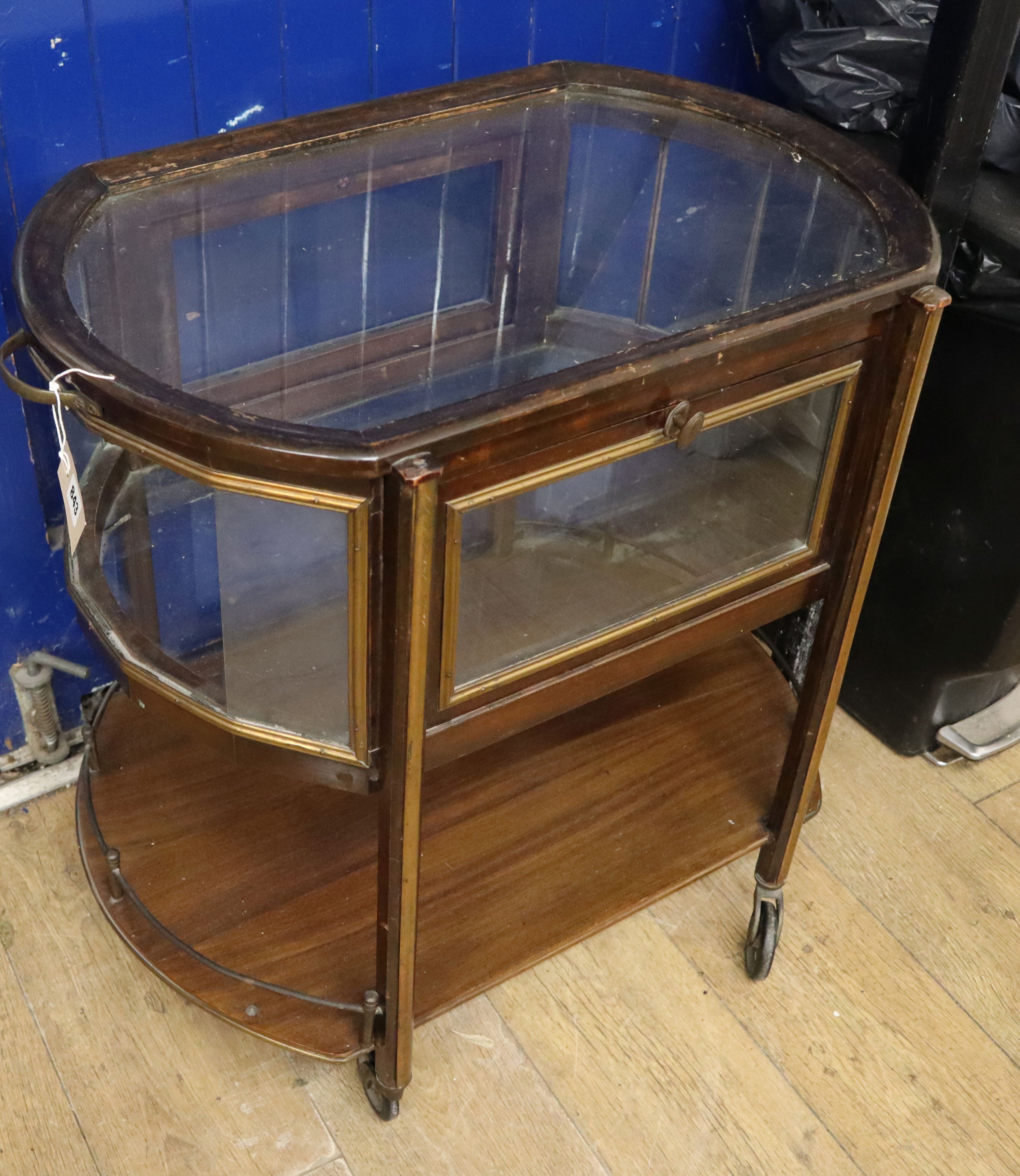 A two-tier drinks trolley of oval form, with glazed upper section and galleried undertier W.72cm