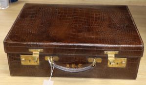 A crocodile skin suitcase in outer canvas case