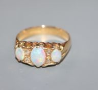 A George V 18ct gold, three stone opal and diamond chip set dress ring, size O.