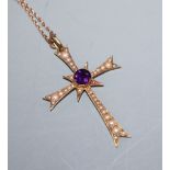 An Edwardian 15ct gold, amethyst and seed pearl set cross pendant, on a yellow metal fine link