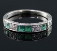 An 18ct and plat, emerald and diamond set half hoop ring, with engraved shank, size N.