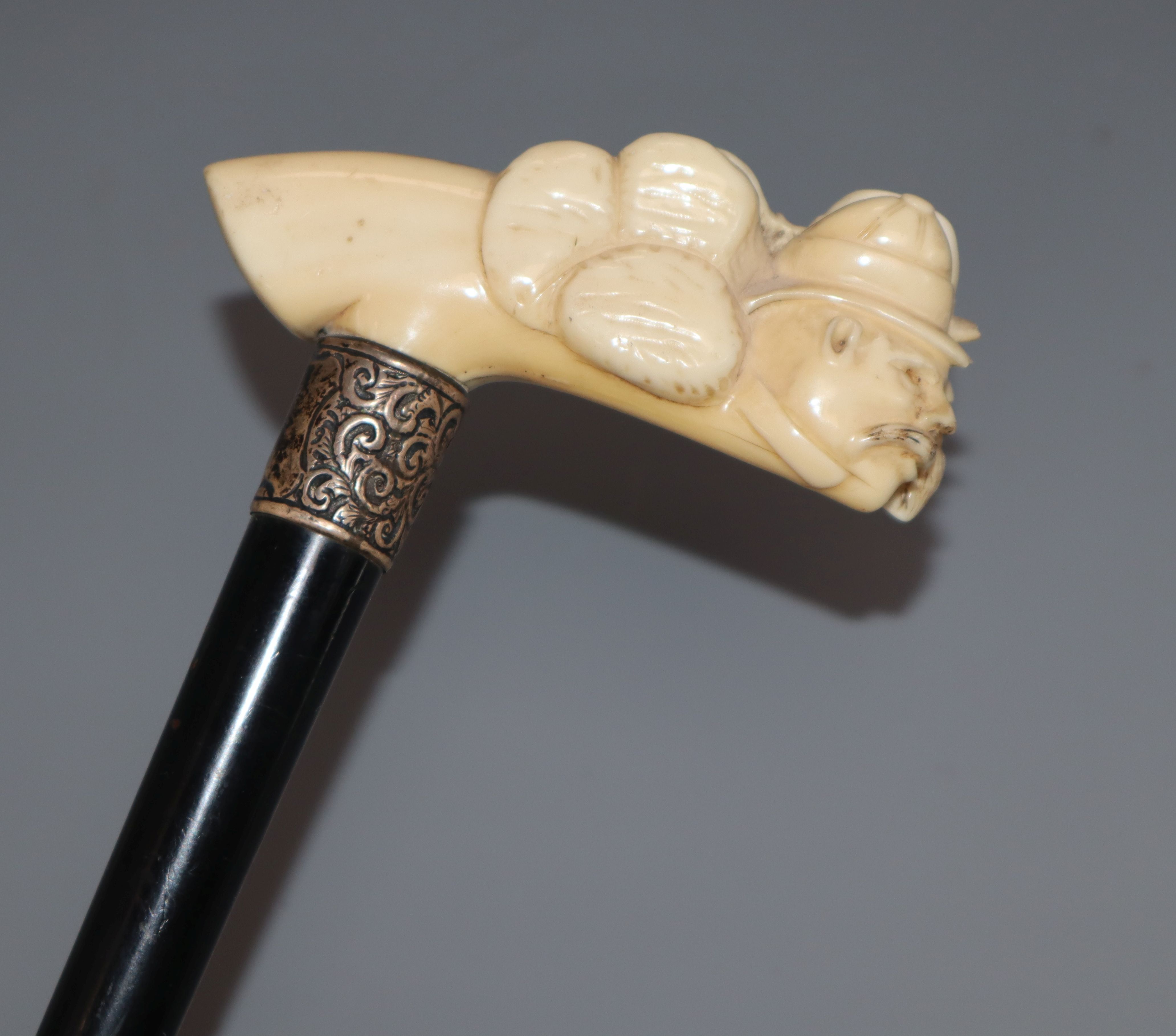 A lacquered walking cane with silver collar and carved ivory handle, in the shape of two warped