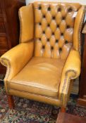 A button back tan leather wing armchair