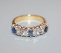 A modern 18ct gold, three stone sapphire and two stone diamond half hoop ring, size N.