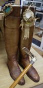 A pair of vintage riding boots with trees and a silver-collared cane riding stick