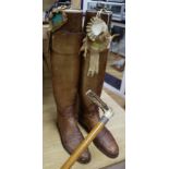 A pair of vintage riding boots with trees and a silver-collared cane riding stick