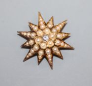 An Edwardian yellow metal, seed pearl and diamond set starburst brooch, 26mm.