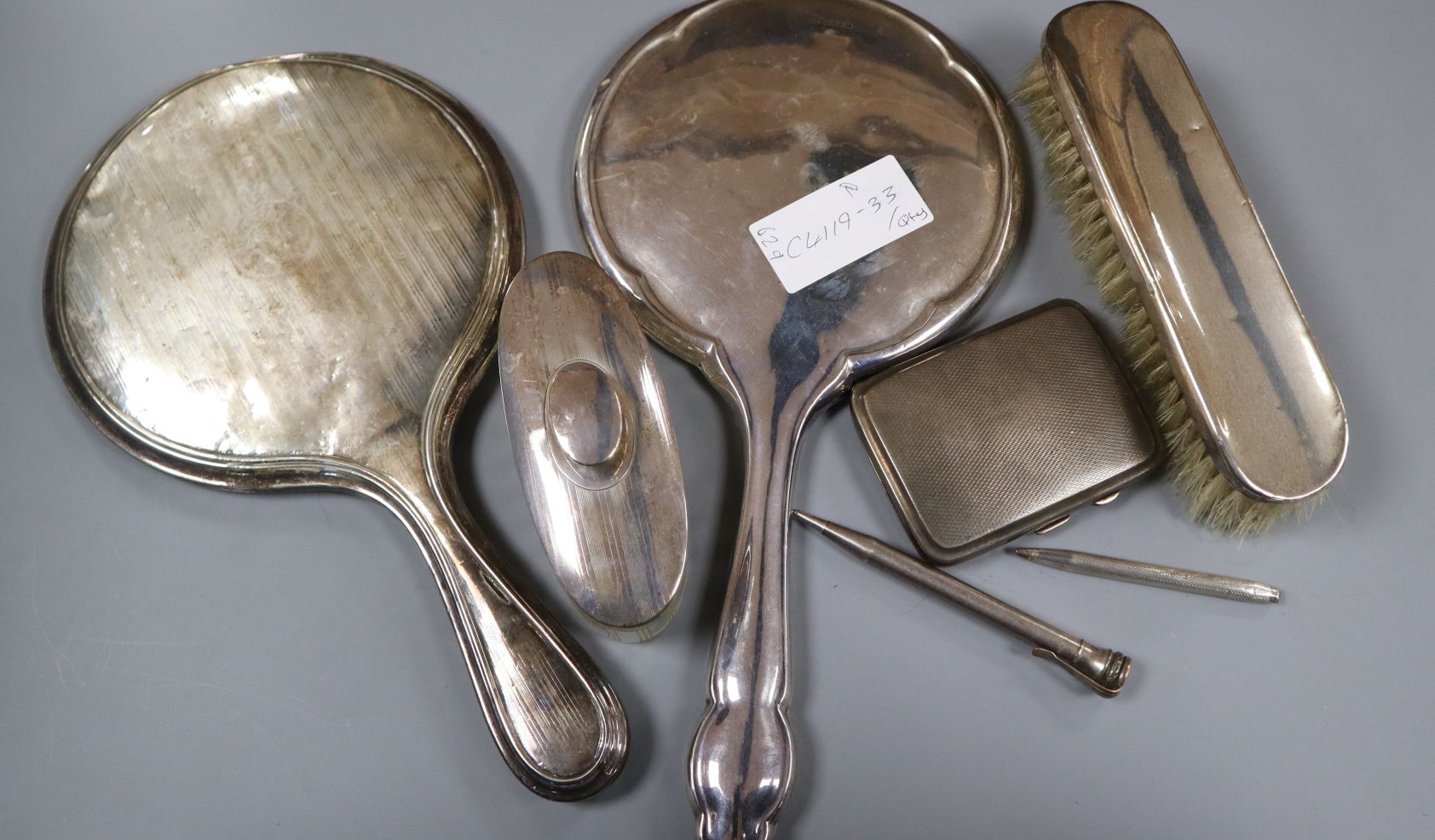 Two silver hand mirrors and four other items including silver cigarette case, brush and toilet jar.