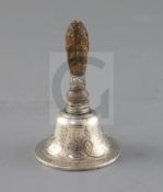 A 19th century continental silver hand bell, with engraved scroll decoration and carved wood?
