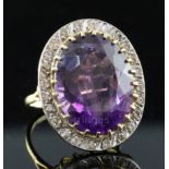 A large gold, amethyst and diamond set oval dress ring, the oval cut amethyst bordered by twenty