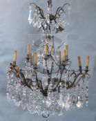 An Italian bronze and cut glass twelve light chandelier, hung with flower and lappet and tear shaped