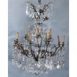 An Italian bronze and cut glass twelve light chandelier, hung with flower and lappet and tear shaped