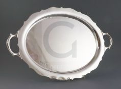 A George V silver two handled shaped oval tea tray, William Suckling Ltd, on four scroll feet,