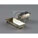 An Edwardian novelty silver pin cushion, modelled as a pig at a trough, by Adie & Lovekin,