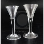Two drawn trumpet wine glasses, c.1750, the larger example with tear drop to the plain stem, on a