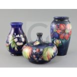 Two Moorcroft vases in 'clematis' and 'pansy' and a similar 'leaf and berry' jar and cover, 1920/