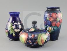 Two Moorcroft vases in 'clematis' and 'pansy' and a similar 'leaf and berry' jar and cover, 1920/