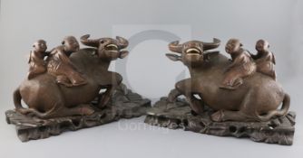 A pair of Chinese hardwood groups of children riding a buffalo, early 20th century, on separate
