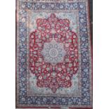 A Kirman red ground carpet, with central foliate medallion in a field of scrolling foliage, with