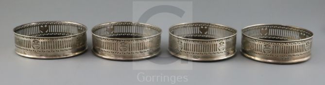 A set of four George V pierced silver wine coasters by Harry Freeman, with beaded borders and turned