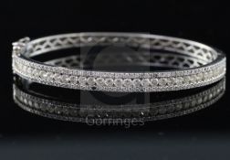 A modern 18k white gold and three row diamond set hinged bracelet, inner measurement approximately