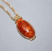 A 9ct yellow gold-mounted oval amber pendant on yellow metal chain (tests as 9ct)